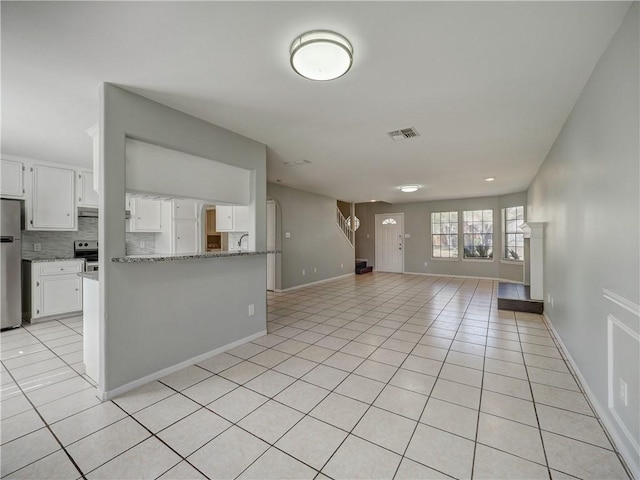 unfurnished living room with light tile patterned floors, visible vents, and baseboards