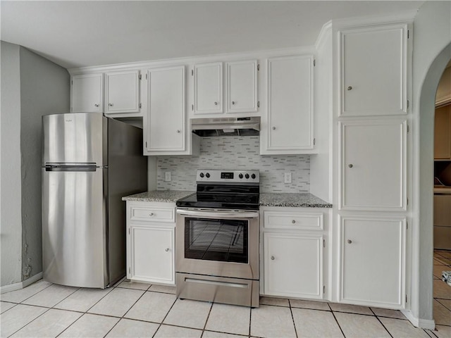 kitchen featuring under cabinet range hood, light tile patterned floors, decorative backsplash, appliances with stainless steel finishes, and white cabinets