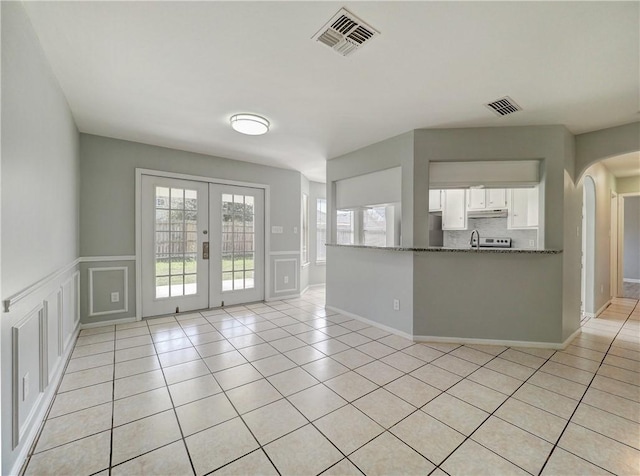 unfurnished room featuring light tile patterned floors, french doors, visible vents, and a healthy amount of sunlight