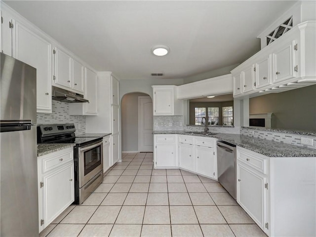 kitchen with light tile patterned flooring, a sink, stainless steel appliances, white cabinets, and under cabinet range hood