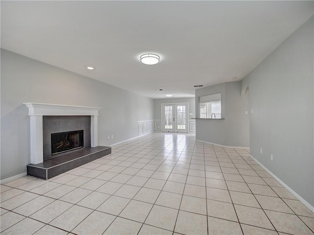 unfurnished living room featuring light tile patterned floors, french doors, baseboards, and a tile fireplace