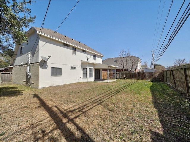 back of house featuring brick siding, a patio area, a fenced backyard, and a lawn