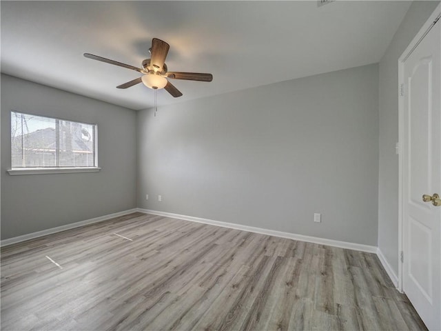 empty room featuring ceiling fan, baseboards, and wood finished floors