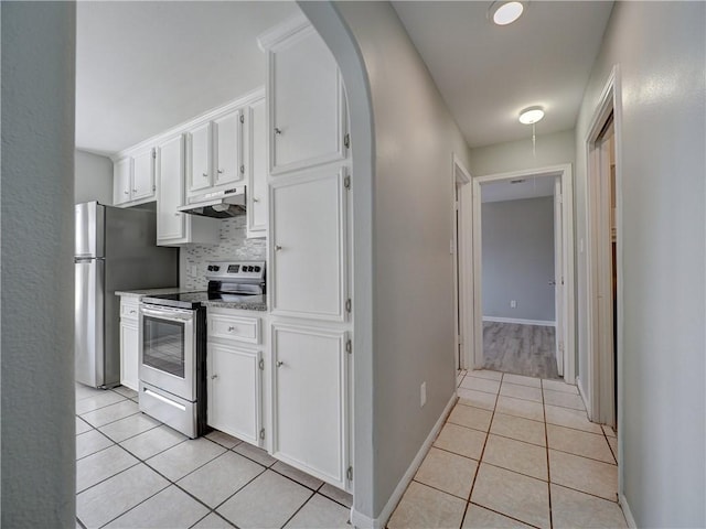 kitchen featuring backsplash, under cabinet range hood, light tile patterned floors, stainless steel appliances, and white cabinetry