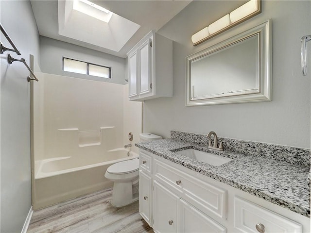 bathroom featuring tub / shower combination, toilet, a skylight, wood finished floors, and vanity