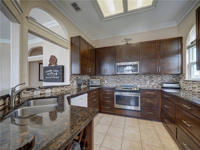 14218 Punta Bonaire Dr, Corpus Christi, TX 78418 - kitchen with stainless steel appliances, decorative backsplash, dark stone countertops, light tile patterned flooring, and ornamental molding