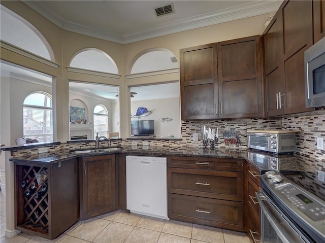 14218 Punta Bonaire Dr, Corpus Christi, TX 78418 - kitchen with stainless steel appliances, dark stone countertops, decorative backsplash, dark brown cabinets, and crown molding