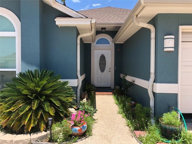 14218 Punta Bonaire Dr, Corpus Christi, TX 78418 - view of exterior entry featuring stucco siding, roof with shingles, and an attached garage