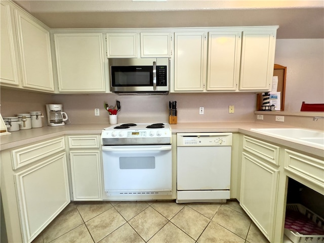 kitchen featuring kitchen peninsula, light tile patterned flooring, white appliances, and sink