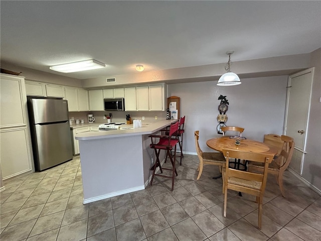 kitchen featuring white cabinetry, kitchen peninsula, decorative light fixtures, light tile patterned floors, and appliances with stainless steel finishes