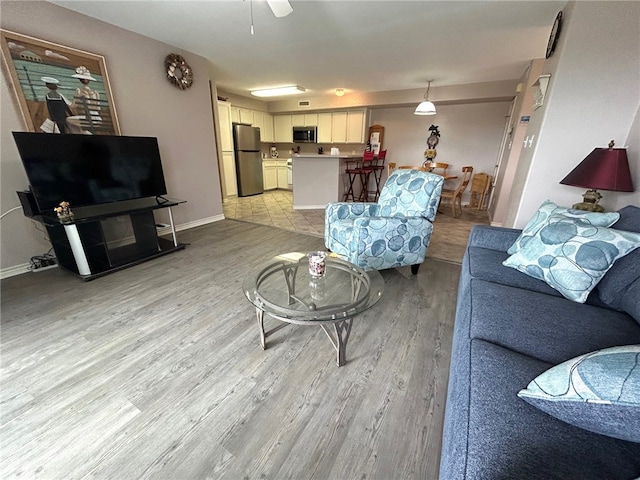 living room featuring ceiling fan and light hardwood / wood-style floors