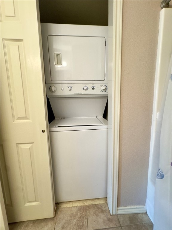 laundry room featuring light tile patterned flooring and stacked washer and clothes dryer