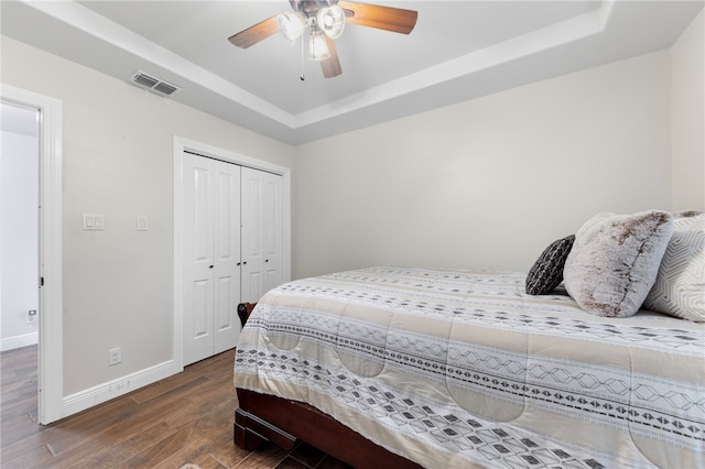 bedroom featuring ceiling fan, dark hardwood / wood-style floors, a closet, and a raised ceiling