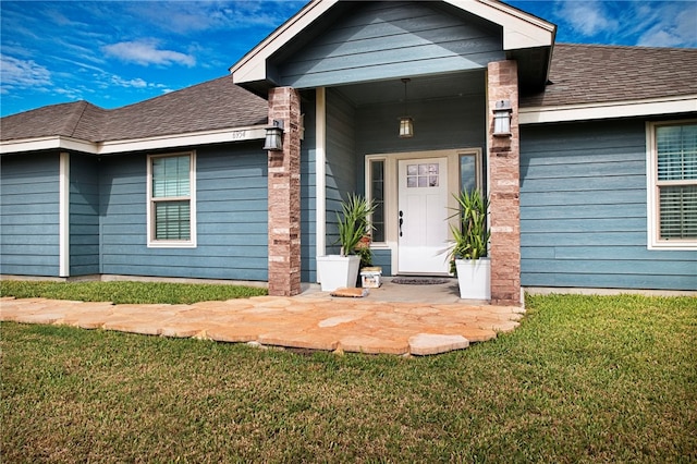 view of exterior entry featuring a lawn