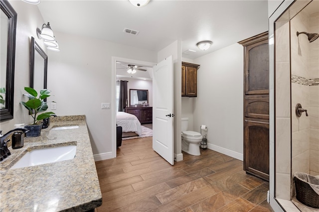 bathroom featuring toilet, tiled shower, hardwood / wood-style floors, and ceiling fan