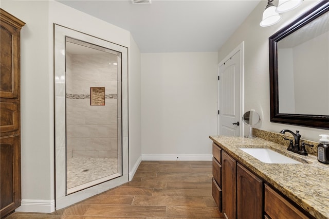 bathroom with hardwood / wood-style floors, tiled shower, and vanity