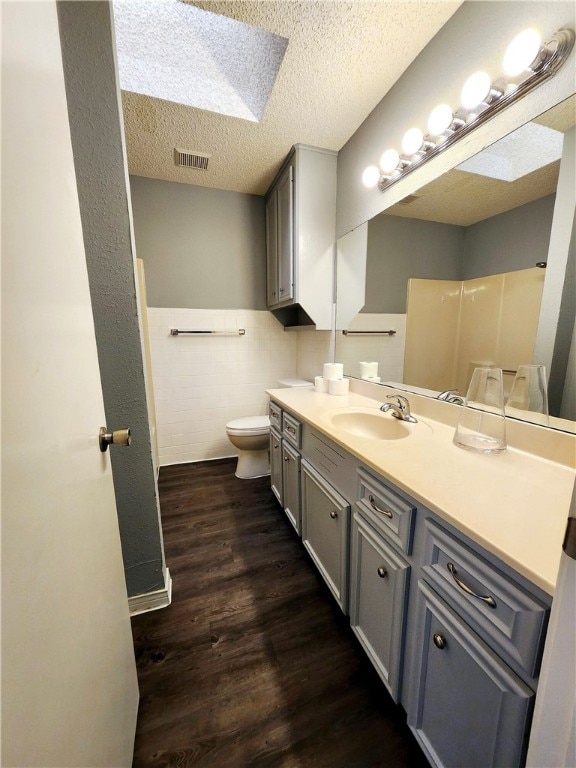 bathroom with vanity, a textured ceiling, hardwood / wood-style floors, toilet, and a skylight