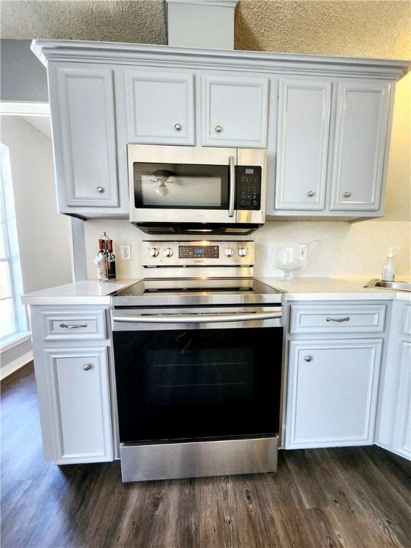 kitchen with white cabinets, dark hardwood / wood-style flooring, and appliances with stainless steel finishes