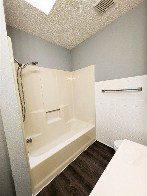 bathroom featuring hardwood / wood-style floors, a textured ceiling, toilet, and shower / bath combination