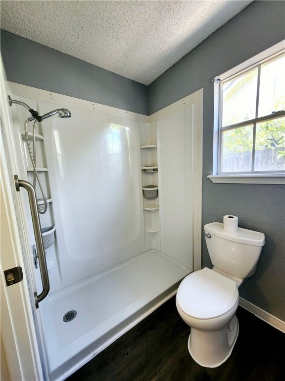 bathroom with walk in shower, a textured ceiling, hardwood / wood-style flooring, and toilet