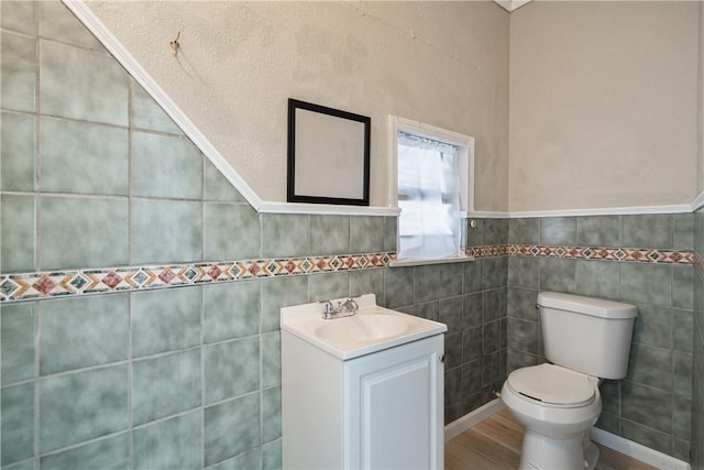 bathroom featuring vanity, tile walls, and toilet