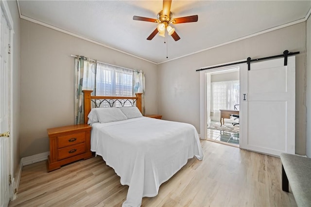 bedroom with a barn door, light hardwood / wood-style floors, ceiling fan, and ornamental molding