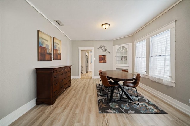 dining area with crown molding and light hardwood / wood-style flooring