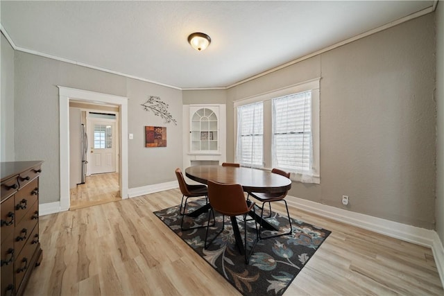 dining space featuring light wood-type flooring, ornamental molding, and a wealth of natural light