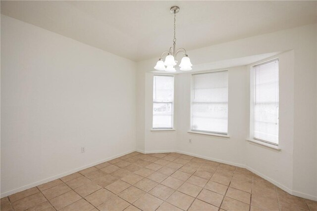 unfurnished room featuring plenty of natural light, light tile patterned flooring, and a notable chandelier