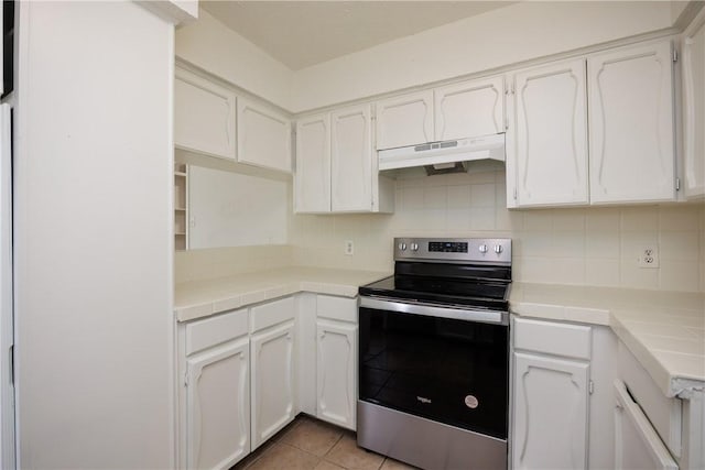 kitchen featuring tile countertops, white cabinetry, under cabinet range hood, and stainless steel range with electric cooktop
