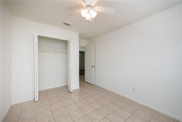 unfurnished bedroom featuring visible vents, a closet, baseboards, a ceiling fan, and light tile patterned floors