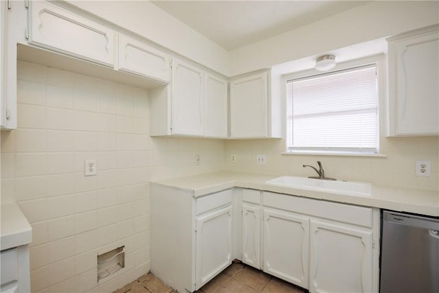 kitchen with stainless steel dishwasher, a sink, white cabinetry, and light countertops