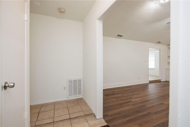 spare room featuring visible vents, baseboards, and wood finished floors