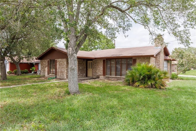 single story home with brick siding, a chimney, and a front lawn