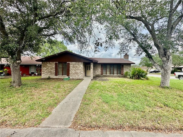 ranch-style home with brick siding, a front lawn, and a chimney