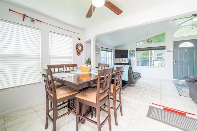 dining space with a ceiling fan, light marble finish floors, arched walkways, and lofted ceiling