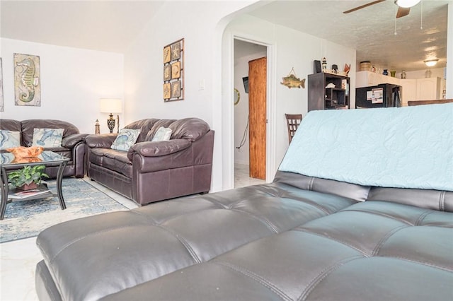 living area featuring a ceiling fan and arched walkways