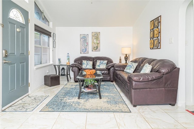 living area with light marble finish flooring, arched walkways, baseboards, and lofted ceiling