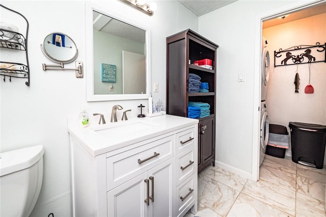 bathroom featuring stacked washer and clothes dryer, marble look tiles, vanity, and toilet
