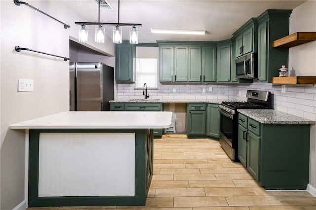 kitchen with sink, stainless steel appliances, tasteful backsplash, green cabinets, and pendant lighting