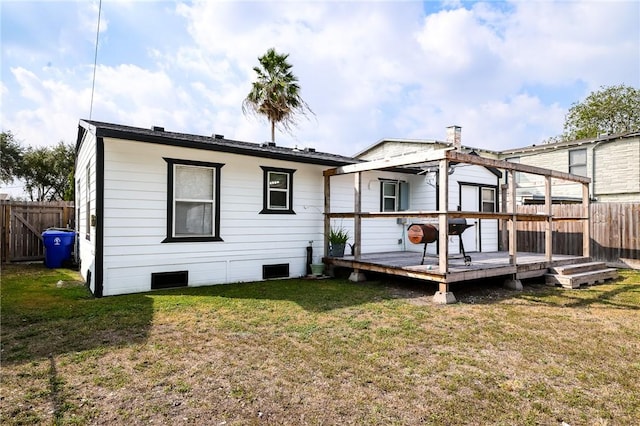 back of property with a deck and a yard