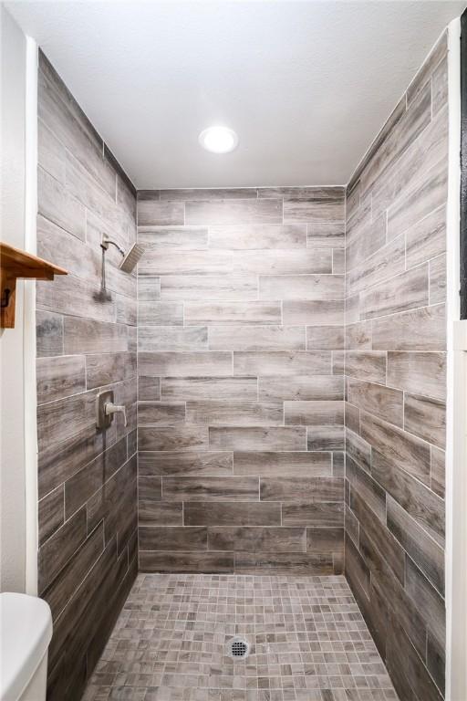 bathroom with tiled shower and toilet