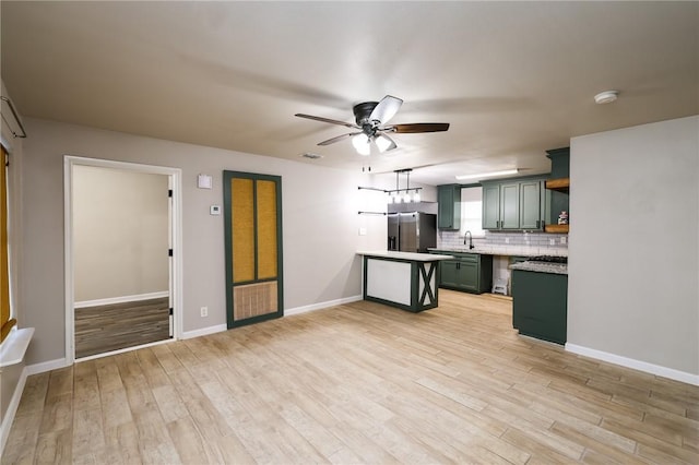 kitchen featuring sink, hanging light fixtures, green cabinets, stainless steel fridge with ice dispenser, and backsplash