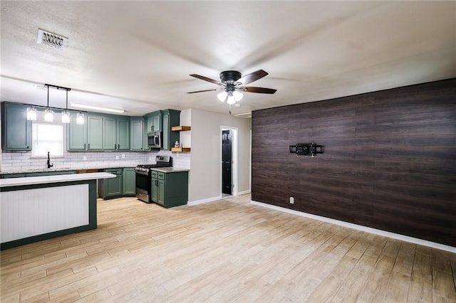 kitchen featuring ceiling fan, stainless steel appliances, green cabinets, backsplash, and decorative light fixtures