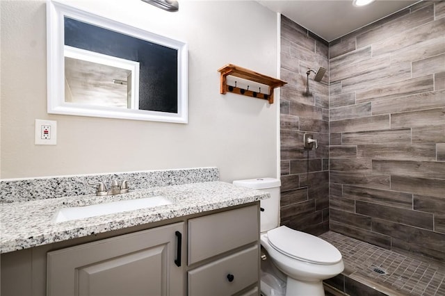 bathroom featuring tiled shower, vanity, and toilet