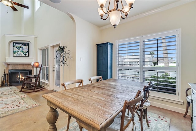 carpeted dining area featuring ceiling fan with notable chandelier, ornamental molding, and a fireplace