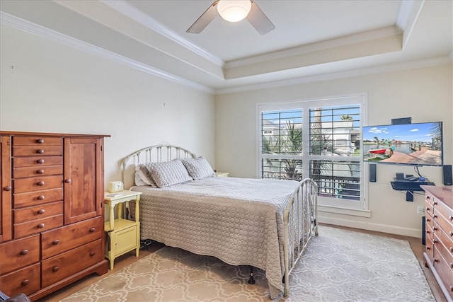 bedroom featuring crown molding, light hardwood / wood-style floors, ceiling fan, and a raised ceiling