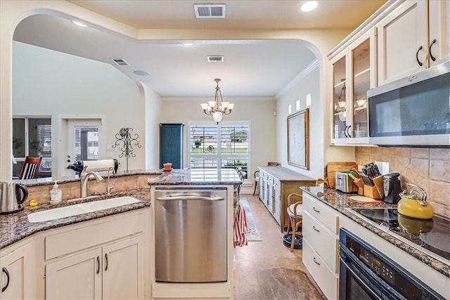 kitchen with white cabinets, appliances with stainless steel finishes, sink, and an inviting chandelier