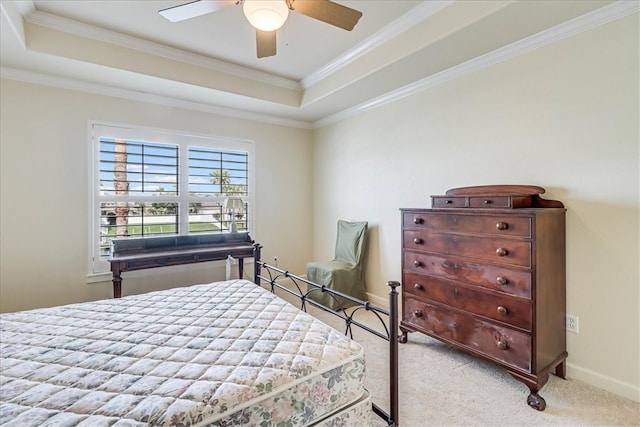 carpeted bedroom featuring a tray ceiling, ceiling fan, and crown molding