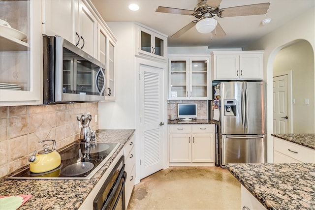 kitchen featuring white cabinetry, appliances with stainless steel finishes, dark stone countertops, ceiling fan, and decorative backsplash